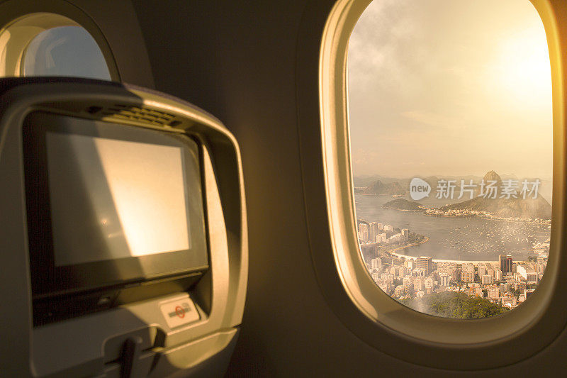 巴西里约热内卢，从机场起飞后，从飞机经济舱座位的窗户俯瞰日落/日出的天空。